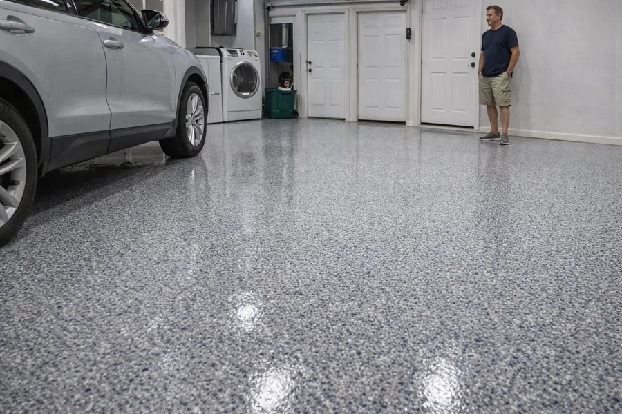 Finished epoxy floor repair result — restored decorative flake garage floor with car parked and satisfied homeowner