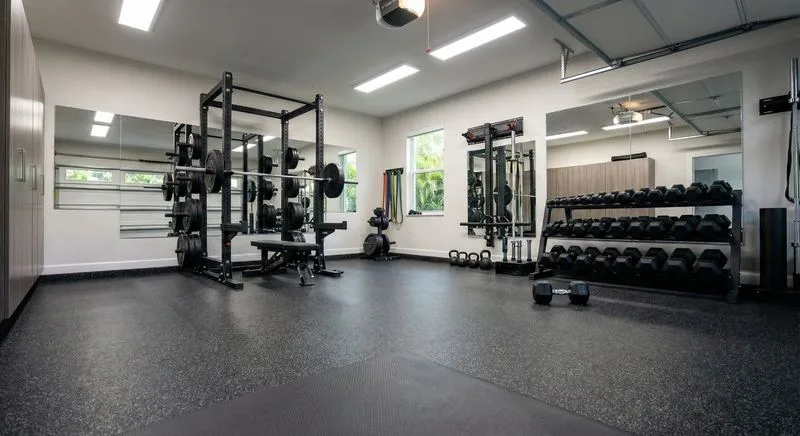 Well-equipped home gym in converted garage with dark charcoal flake epoxy floor